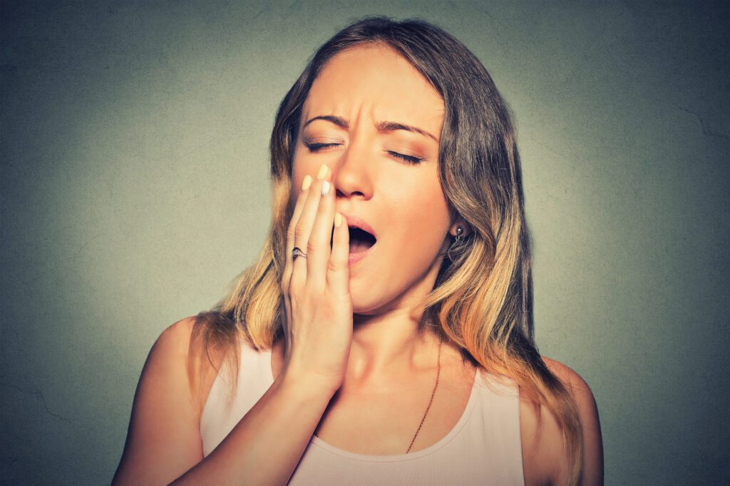 Closeup portrait sleepy young woman with wide open mouth yawning eyes closed looking bored isolated on gray wall background