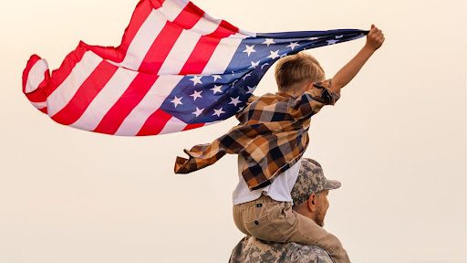 boy on dads shoulder holding american flag