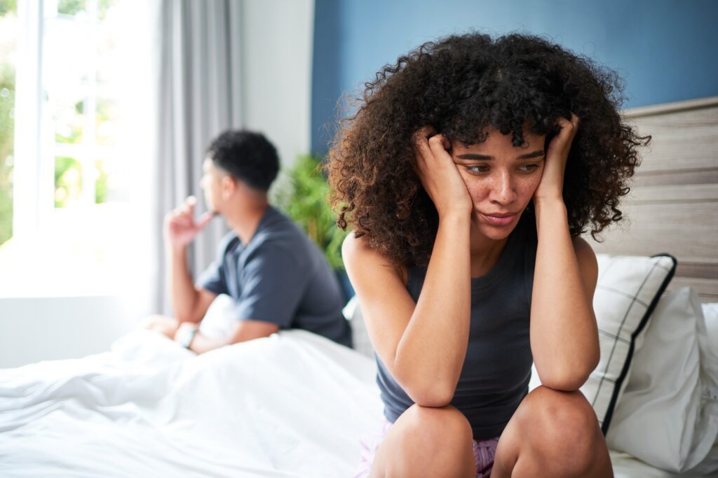 Distressed Young Couple Experiencing Relationship Struggles in a Bright Bedroom Setting