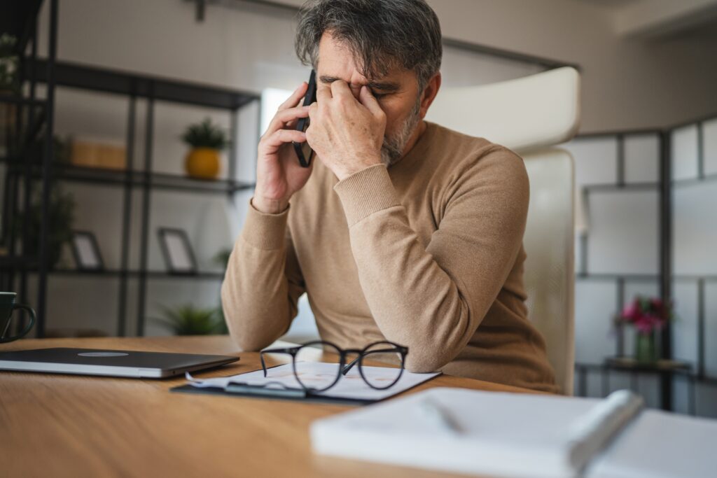 tired man rubbing his eyes at his desk